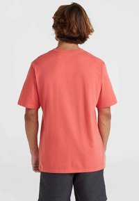 Camiseta de manga corta en algodón color coral, con cuello redondo y un ajuste relajado. Textura suave sin patrones o acentos visibles.