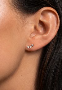 Drei kleine, runde, funkelnde Diamanten sind in einem Design für einen Silberohrmanschette eingesetzt und entlang der Kurve des Ohrläppchens platziert.
