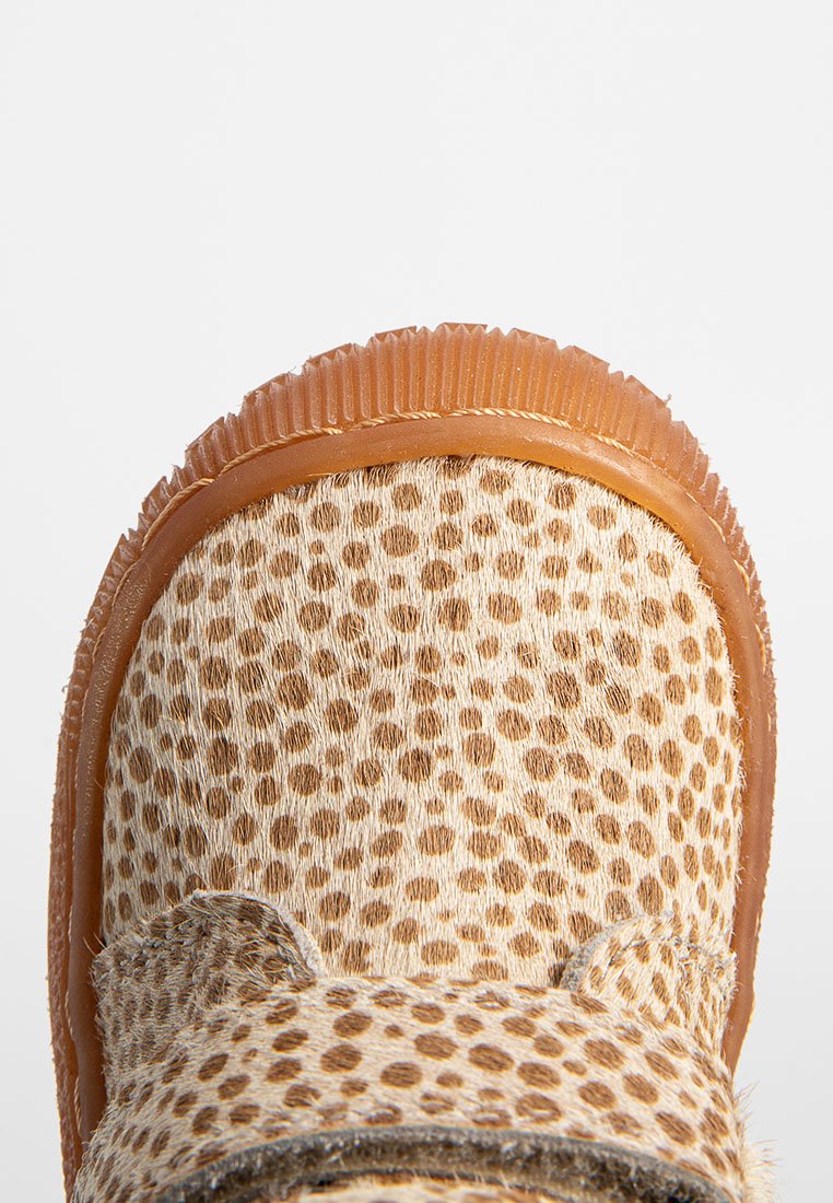 Nahaufnahme eines braunen Schuhs mit Gummisohle, der von beigem und braun geschecktem Fell an der Zehe und den oberen Bereichen bedeckt ist.