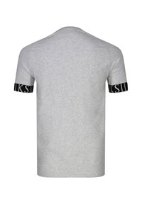 T-shirt grigio chiaro a maniche corte con bande nere sulle maniche che mostrano lettere bianche parzialmente visibili, vista da dietro.