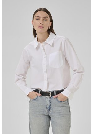 White button-up shirt with long sleeves, a chest pocket, and a folded collar, worn with light blue denim jeans and a black belt.