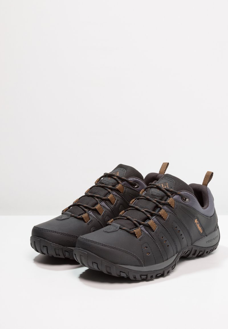 Czarne buty na zewnątrz z teksturowaną cholewką, wiązanym wzorem i brązowymi akcentami. Posiadają solidną podeszwę zapewniającą przyczepność i stabilność.