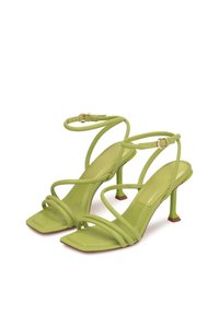 Sandales à talons vernis vertes avec un design à bout carré, des fines lanières et un petit talon carré avec un accent contrastant à la base.