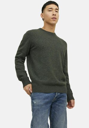 Dunkelgrüner, gestrickter Pullover mit Rundhalsausschnitt und gerippten Bündchen, kombiniert mit hellblauen, verwaschenen Jeans. Enganliegendes Design.
