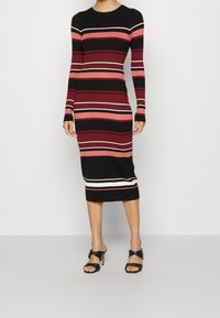 Robe en maille rayée noire, bordeaux et rose, avec manches longues et silhouette ajustée, ornée de rayures blanches en accent à l'ourlet.