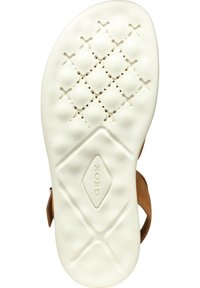 Bruine sandaal met een witte rubberen zool met een gestructureerd patroon en ventilatiegaten. Merkenlogo "GEOX" is in de voetbed gedrukt.