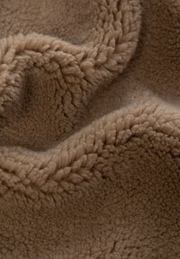 Brun fleece-tyg med en mjuk, texturerad yta, som har ett vågigt mönster och ett varmt, fluffigt utseende.