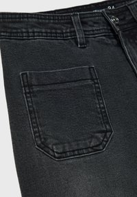 Črne jeans hlače iz denima imajo zadnji žep z izrazitimi pravokotnimi oblikami, šiviljskimi detajli in gladko teksturo.