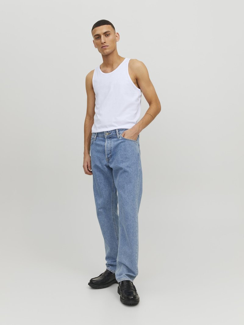 Un débardeur blanc sans manches, un jean bleu clair et des chaussures noires. Le jean a une coupe décontractée et des détails de couture visibles.