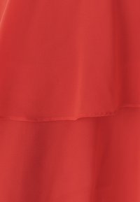Red chiffon fabric with a layered design. Soft, smooth texture. Features a clean hem, with a lightweight and flowing appearance.