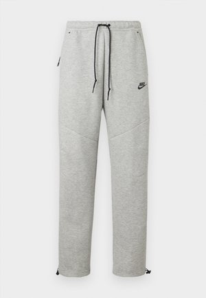 Grå Nike sweatpants med snøre i taljen, sidelommer og elastiske manchetter. Har en glat overflade og kontrastfarvet sort logo-detalje.
