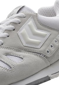 Graue Wildleder-Sneaker mit strukturiertem Finish, weißen Mesh-Akzenten, einer weißen Gummisohle und einem auffälligen grauen Logo an der Seite.