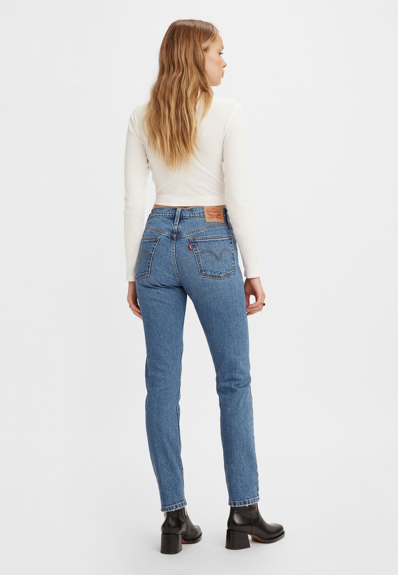 Hellblaue Jeans mit hoher Taille, schlankem Schnitt und dezentem Verblassen. Verfügt über klassische Gesäßtaschen und ein braunes Leder-Logopatch.