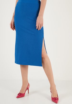 Blue ribbed midi skirt with a side slit. Paired with pink pointed-toe heels. Skirt features a fitted waistband and smooth texture.
