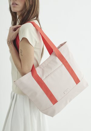 Lyserød tote bag med orange stropper, der har en frontlomme, rektangulær form og en struktureret stofoverflade.