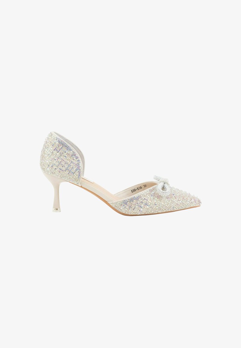 Zapato de tacón adornado con joyas, con punta afilada, gemas transparentes sobre una base blanca y un pequeño lazo decorativo en la punta. Presenta un tacón de aguja.