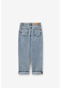 Jean en denim bleu clair avec une coupe ample, cinq poches et ourlets roulés. L'arrière présente une étiquette beige au-dessus de la ceinture.