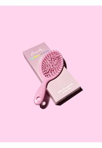 Brosse démêlante rose avec des poils flexibles et un manche lisse, placée à côté de son emballage rose assorti affichant les détails du produit.