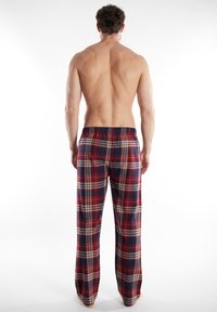 Geruite pyjamabroek in rood, marineblauw en crème; elastische tailleband; zachte textuur; rechte pijpen; lange lengte.