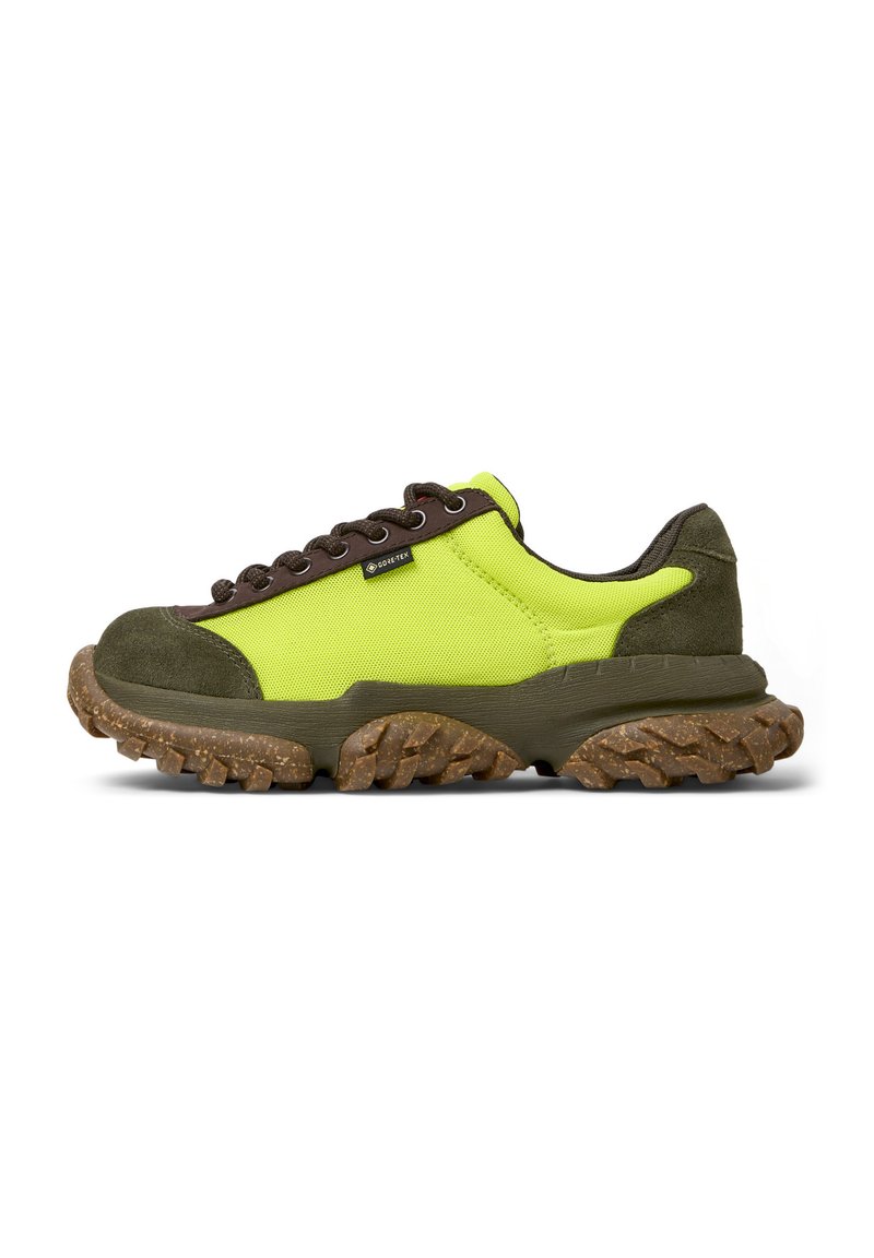 Limettengrüne und braune Sneakers mit einer dicken, strukturierten Sohle und Schnürsenkeln, die ein Gore-Tex-Label an der Seite tragen.