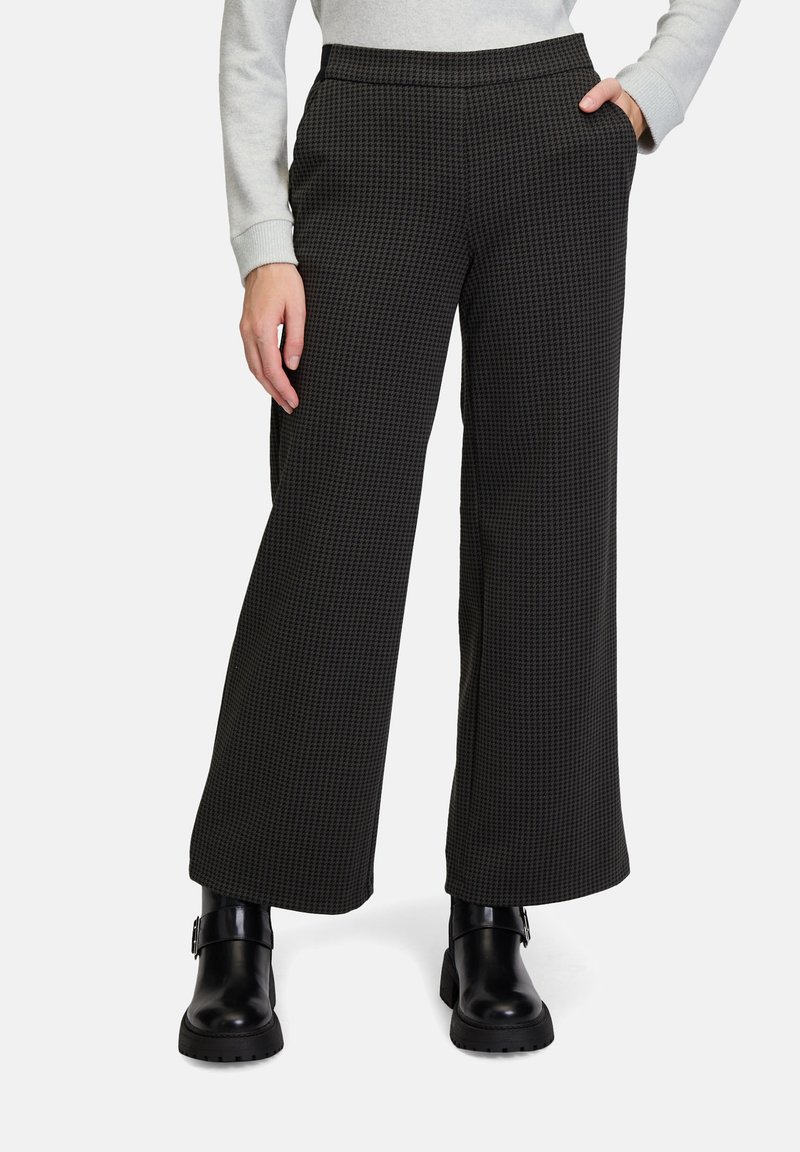 Schwarz karierte weite Hosen mit glatter Textur, ausgestattet mit zwei Seitentaschen und einem flachen Bund. Kombiniert mit schwarzen Ankle Boots.
