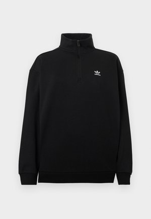 Čierna mikina so štvrtinovým zipsom z mäkkého materiálu, s vysokým golierom, rebrovanými manžetami a malým bielym logom Adidas na hrudi.