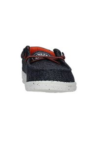 Scarpe di tela blu navy con una tomaia testurizzata, interno arancione a contrasto e suola in gomma bianca maculata. Presentano lacci rosso scuro.