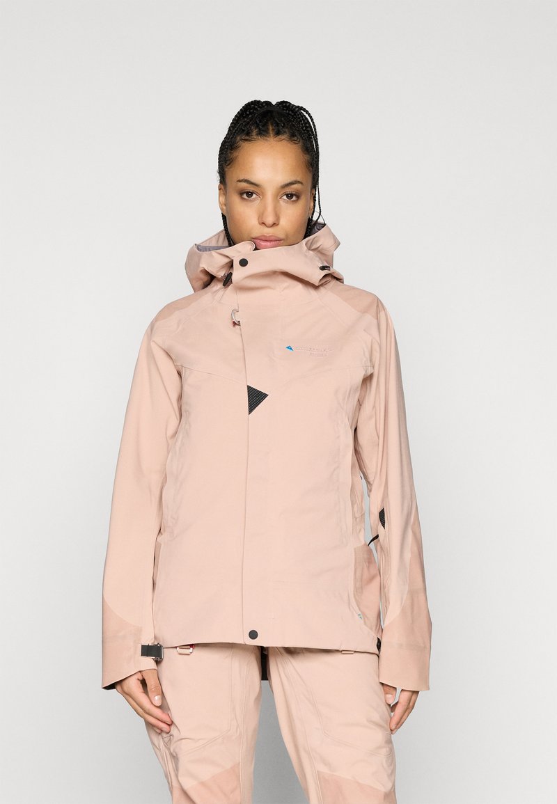 Casaco impermeável rosa claro com gola alta, capuz ajustável e detalhes em preto. Apresenta um design elegante e múltiplos fechos éclair.