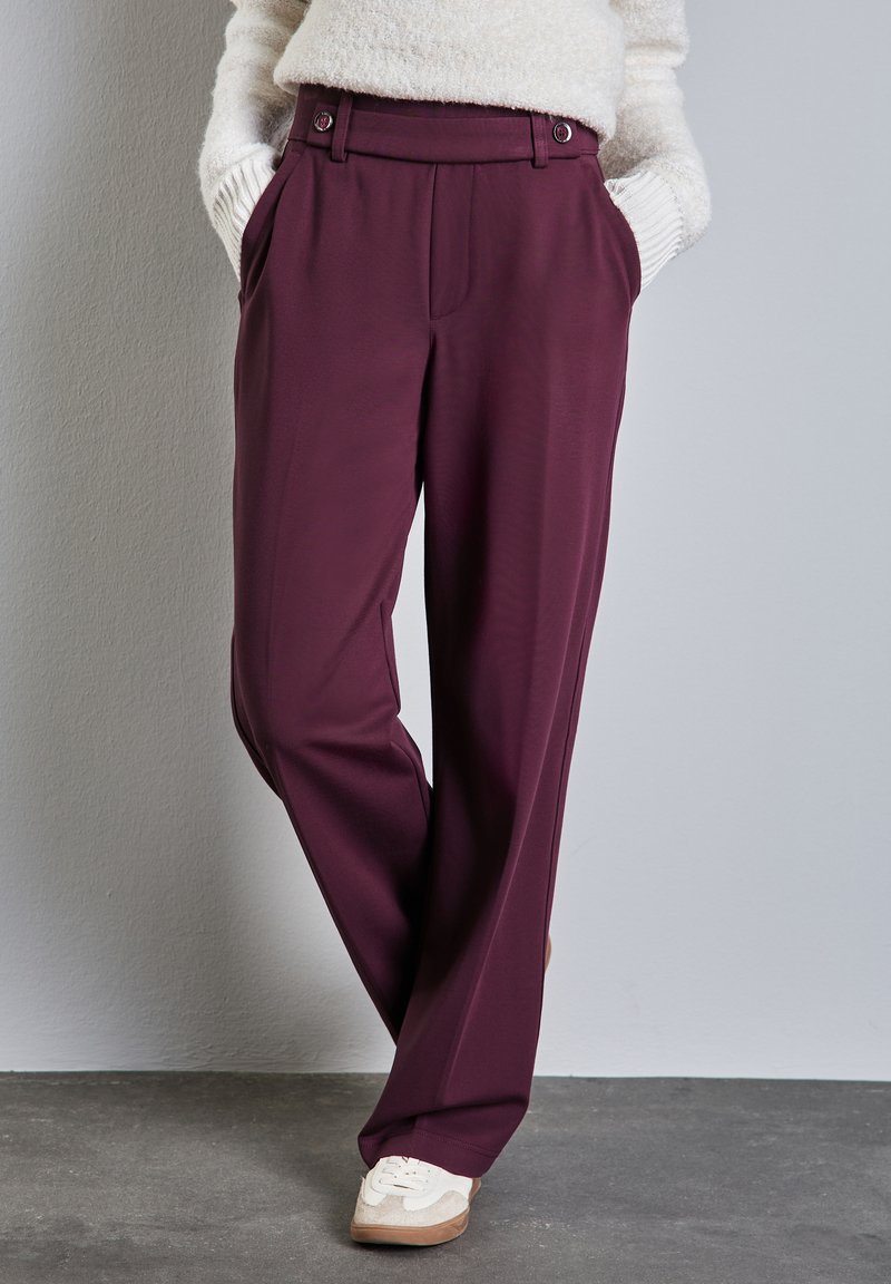 Pantaloni larghi bordeaux con una texture liscia, dotati di due tasche frontali e una piega singola. Chiusura con due bottoni in vita.