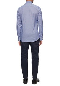 Lichtblauw geruit overhemd met lange mouwen en een button-down kraag, gecombineerd met donkerblauwe broeken en zwarte schoenen. Het heeft een rechte snit en manchetten.