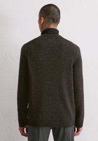 Dunkelbrauner Strickpullover mit einem Rundhalsausschnitt, gerippten Bündchen und Saum. Die Textur wirkt weich und voluminös, entworfen für einen lockeren Sitz.