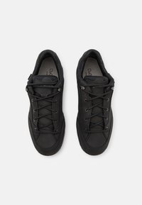 Schwarze Sportschuhe aus strukturiertem synthetischen Material, mit flachen Schnürsenkeln, einem gepolsterten Schaft und einem runden Zehenbereich.