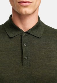 Dunkelgrünes Poloshirt mit Kragen, ausgestattet mit vier Knöpfen. Der Stoff hat eine strukturierte Strickoberfläche. Minimalistisches Design, das sich auf klassischen Stil konzentriert.