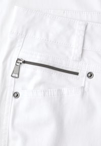 Poche de pantalon blanche avec fermeture éclair horizontale argentée et rivets métalliques sur tissu lisse, montrant une couture détaillée et une passants de ceinture au-dessus de la poche.