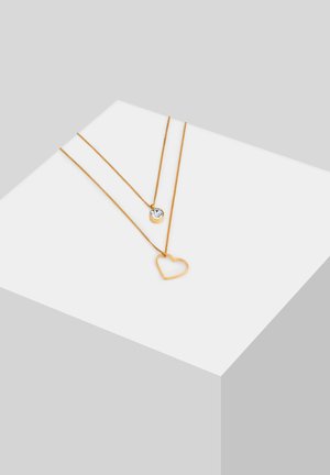 Goldfarbene, mehrschichtige Halsketten mit einem herzförmigen Anhänger und einem runden Kristallakzent, beide mit polierten Oberflächen und feinen Ketten.