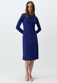 Langärmliges, enganliegendes Kleid in Königblau mit gerafften Details an der Vorderseite, glatter Textur und knielangem Saum.