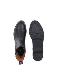 Bottines en cuir noir avec un design brogue, intérieur brun, et semelle en caoutchouc texturée présentant des motifs en forme de cœur.