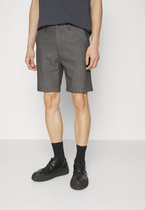 Grijze geruite shorts met een op maat gemaakt ontwerp, voorzakken en een vlakke voorkant. Gecombineerd met zwarte sneakers en zwarte crew sokken.