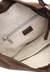Brown suede handbag interior with beige fabric lining, one zippered pocket, and a label patch. Smooth texture, minimalist design.