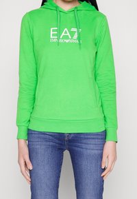Felpa con cappuccio verde con coulisse, tasca frontale e logo bianco EA7 Emporio Armani. Realizzata con materiale morbido e flessibile.