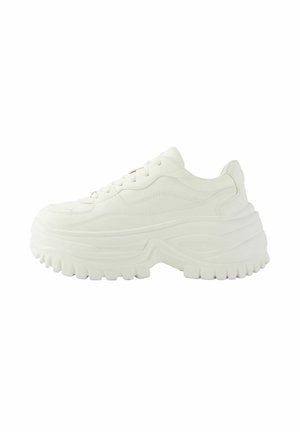 Chunky white sneaker with thick, textured sole, lace-up front, and subtle stitched panel design in a side profile view.