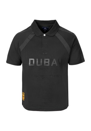 Polo noir à manches courtes avec col, texte « DUBAI Polo Club Emirates World Championship 2026 » sur le devant, et un petit patch jaune en bas.