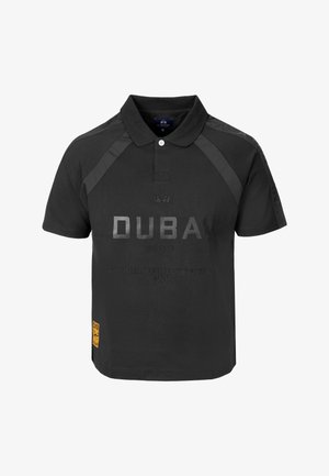Schwarzes kurzärmeliges Poloshirt mit Kragen, mit dem Text „DUBAI Polo Club Emirates World Championship 2026“ auf der Vorderseite und einem kleinen gelben Fleck unten.