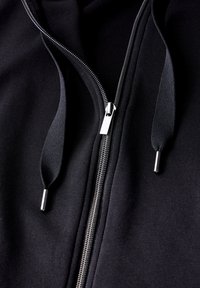 Hoodie zippé noir avec une texture lisse, une fermeture éclair en métal et des cordons de serrage avec des embouts en métal. Design simple sans motifs ni graphiques.