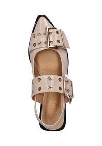 Beige sandalen met spitse neus en glanzende afwerking, voorzien van dubbele gespbandjes, gouden ogen en een zwarte hakaccent. Platte zool.