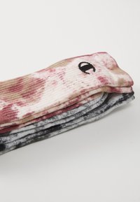Többszínű zoknik, amelyek tye-dye mintázatúak rózsaszín, bézs és szürke színekben. Az anyag lágy kinézetű, bordázott textúrával rendelkezik. Kis fekete szem részlet.