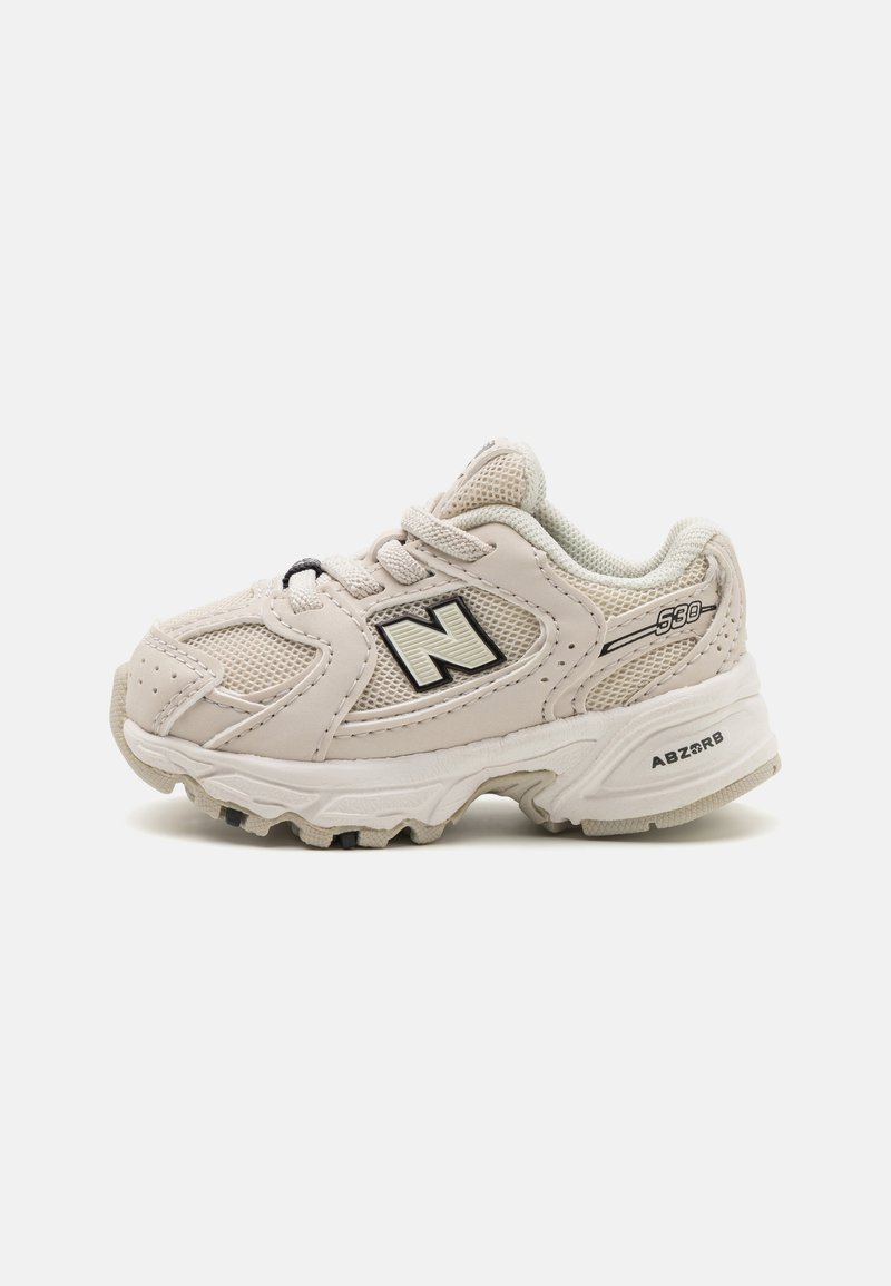 Light beige athletic shoes with mesh upper, padded collar, black accents, logo on side, and textured rubber sole. Model 530.