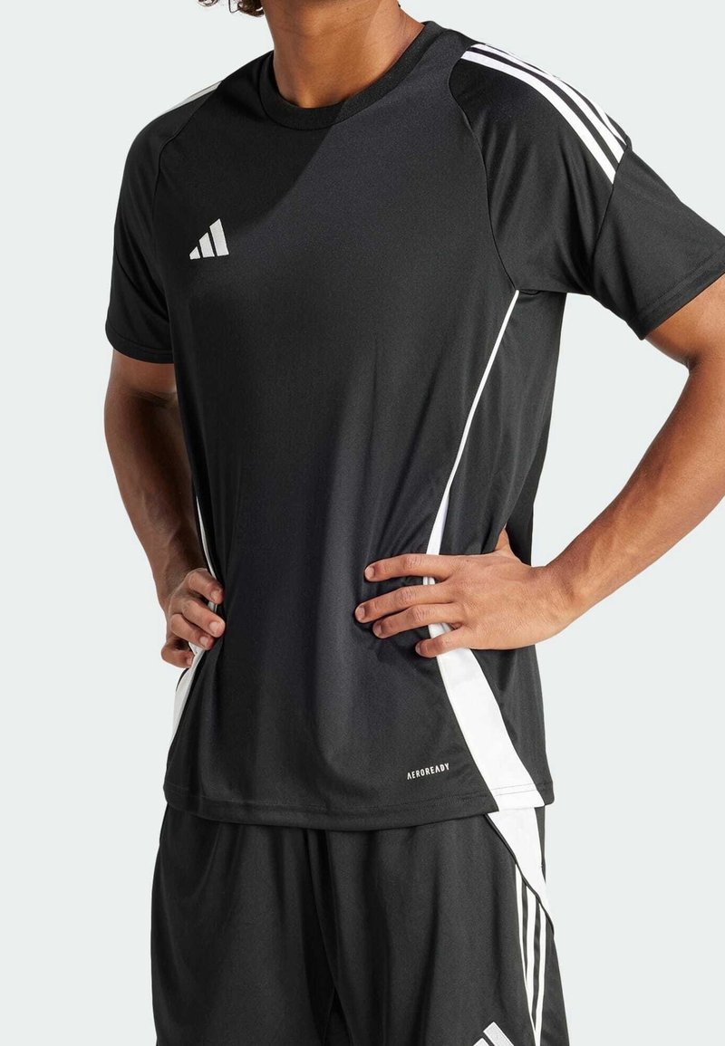 Camiseta deportiva negra con detalles blancos, con cuello redondo, mangas cortas y paneles laterales. Fabricada con material que absorbe la humedad, etiquetada como "AEROREADY".