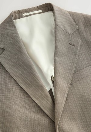 Kerge pruun triibuline bleiser sileda beeži voodriga. Omab klapiga krae ja rinna taskut. Materjal näib tekstuurne ja vastupidav.