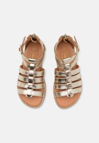 Metallic gold Sandalen mit mehreren horizontalen Riemen, verstellbarem Knöchelriemen und glatter, hellbrauner Innensohle. Flache Sohle mit gestickten Details.